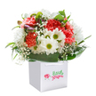 Uplifting and elegant, this Keston-crafted bouquet captures the essence of celebration within a modern white gift bag, inviting feelings of joy from the very first glance. Creamy coral and peach carnations unfurl their abundant ruffled petals, blending harmoniously with white daisy-like flowers crowned by sparkling green-yellow centers. Playful clusters of baby's breath drift throughout, adding a feathery softness reminiscent of a light spring shower over Keston's rural paths. Along the arrangement's edge, a few unopened buds with a quiet wash of purple signal stories yet to unfold, bringing both depth and a whisper of anticipation. Encased by glossy, deep green foliage that echoes the verdant woodlands along Keston Road, the bouquet's full, rounded shape is a declaration of care and skill from talented florists rooted in the community. Resting in a clean, square bag with sturdy ribbons, the design speaks to convenience and thoughtfulness-ready for delivery to any doorstep, or for offering as a radiant gift to mark an anniversary, birthday, or to simply uplift someone's spirits in Keston. Every stem is carefully chosen and arranged to create a harmonious effect-fresh, expressive, and unmistakably crafted with local pride.